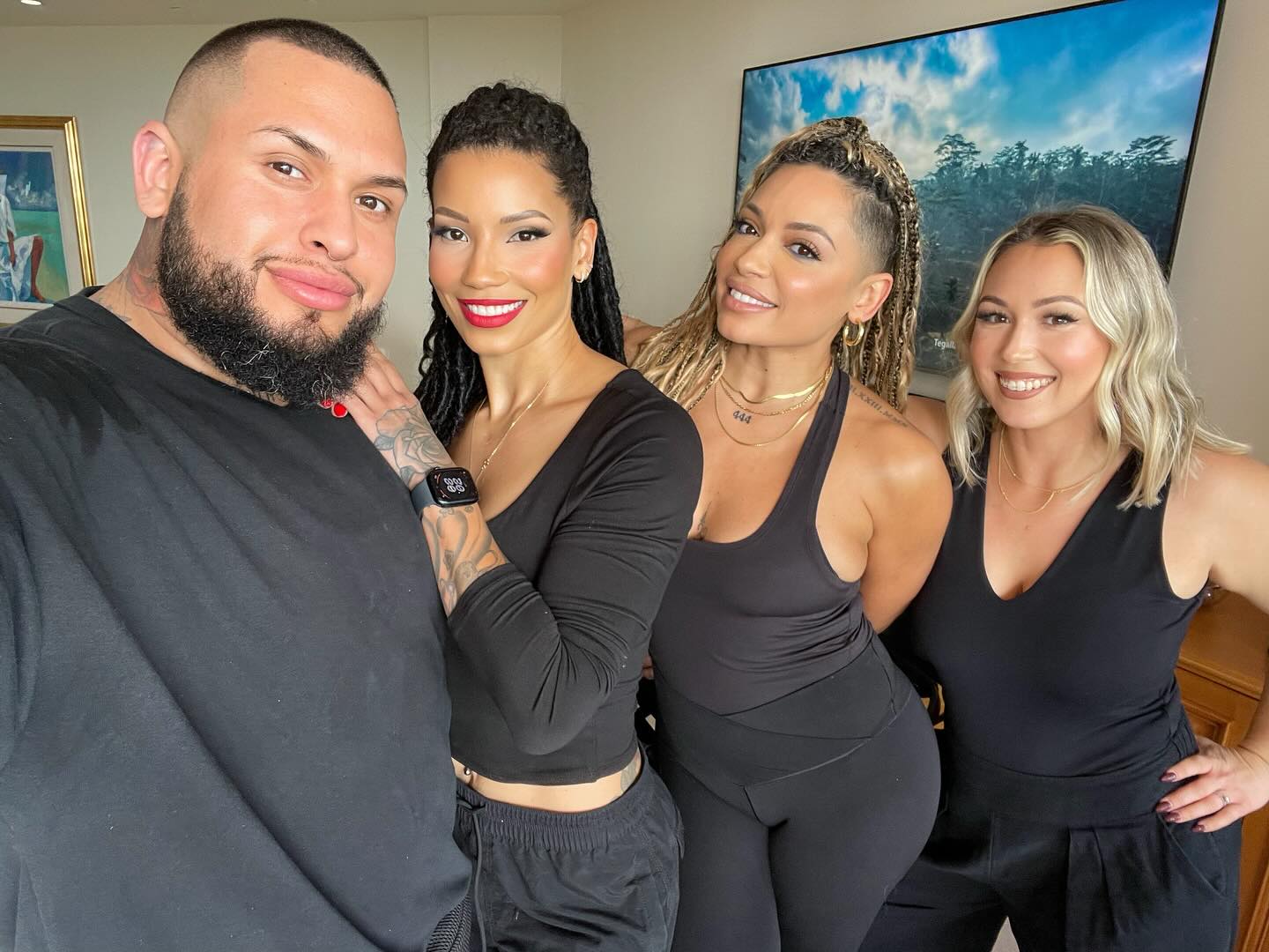 A group photo featuring Aaron Escobar, a makeup artist and owner of Esco Art & Co, alongside Deanna Jones and two other individuals, all dressed in black. They are smiling warmly in a well-lit indoor setting.